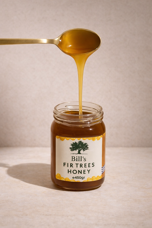 Gold spoon drizzling amber fir tree honey into an open jar of Bill's Fir Trees Honey
